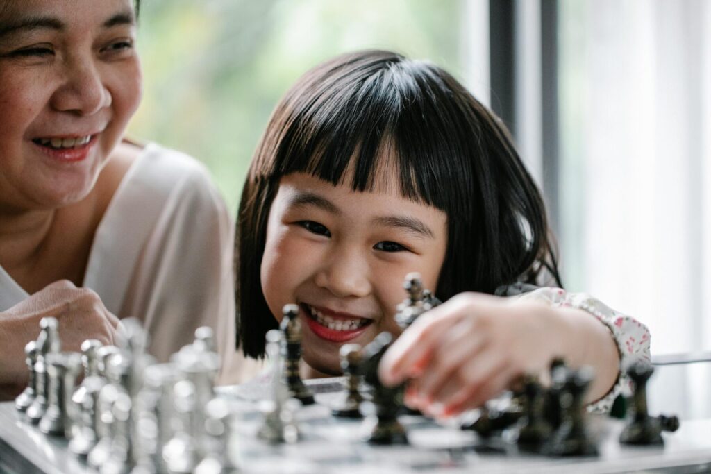child smiling while playing chess with parent showing positive learning experience
