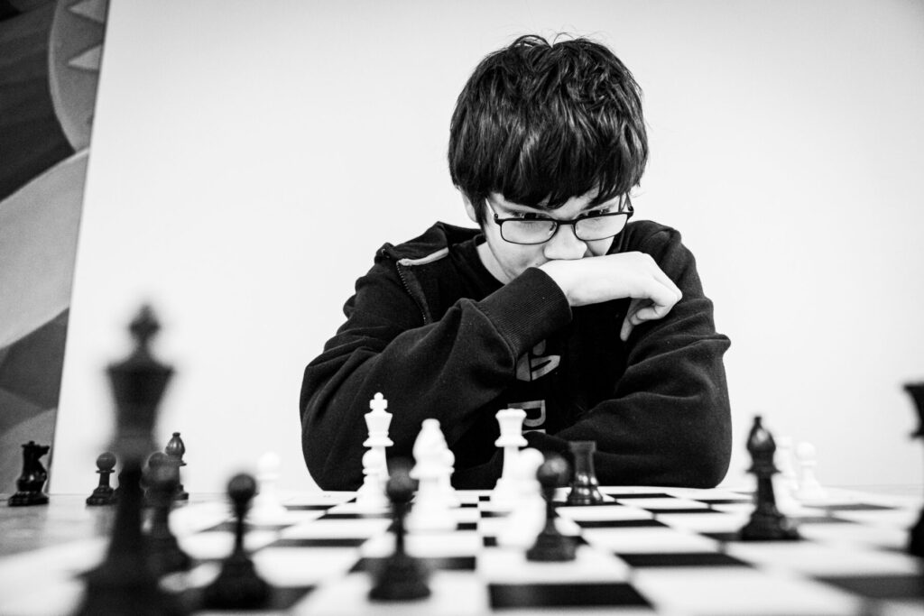 child looking frustrated while playing chess representing fear of starting late